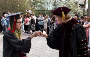 President Jebb fist bumping student wearing regalia