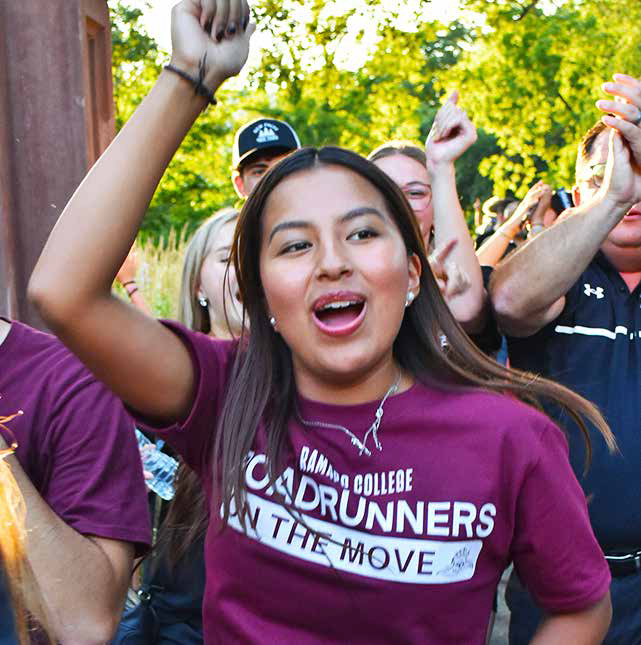 Student wearing a maroon Ramapo College t-shirt, cheering by the arch