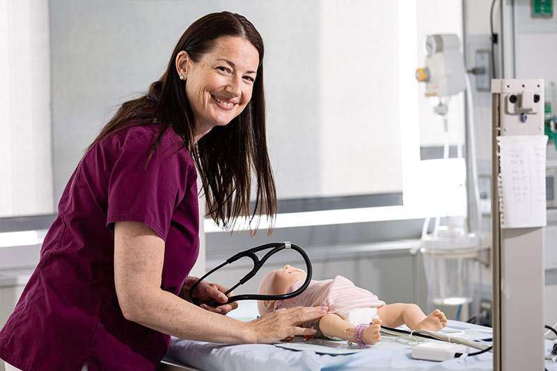 Doctor of Nursing Practice (DNP) student practicing on baby manikin