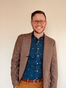 person in glasses and a sports coat smiling