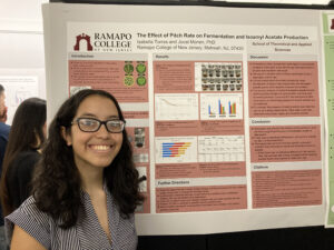 Student posing in front of their research poster.