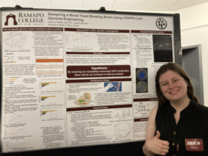 Student posing in front of their research poster.