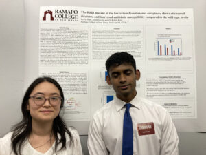 2 students posing in front of their research poster.