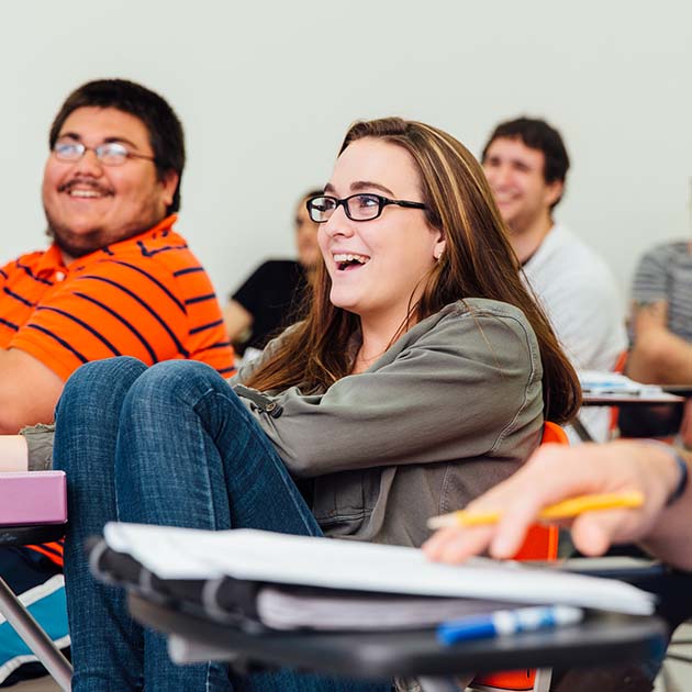 Image focused in a student wearing glasses in a class sitting at a desk