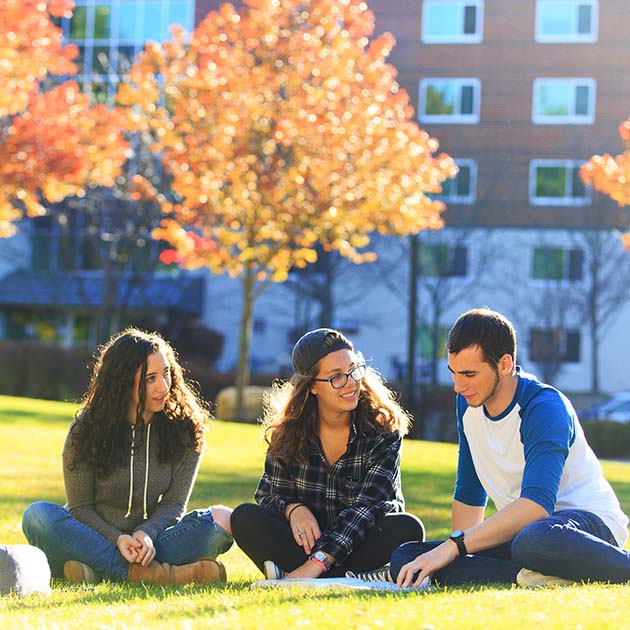 Students sitting cross-legged outside a residence hall