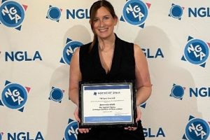 Amanda Riehl holds her Phillipi award in front of the NGLA step and repeat