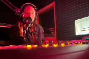 Student at sound board in radio station booth
