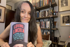 Woman poses with a book in front of her.